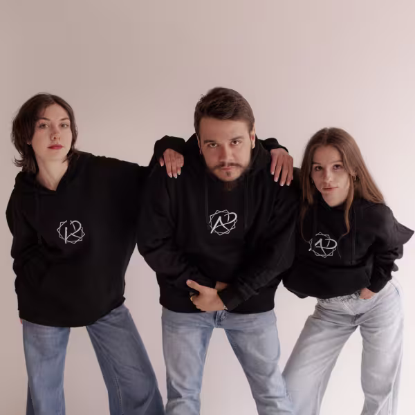 Trzy osoby w bluzach nachylają się do  obiektywu